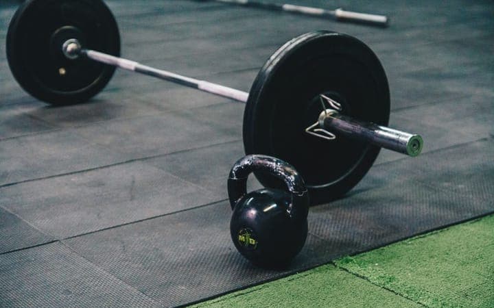 A barbell and kettlebell on a gym floor