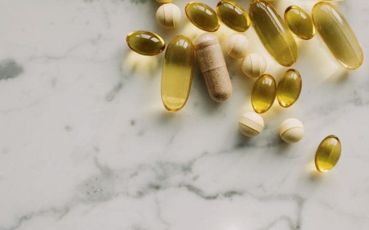 Assorted supplement capsules and tablets on a marble surface